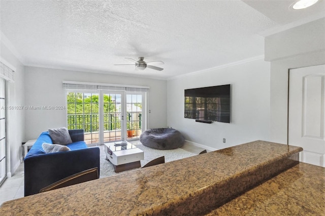 living room featuring ornamental molding, ceiling fan, and a textured ceiling