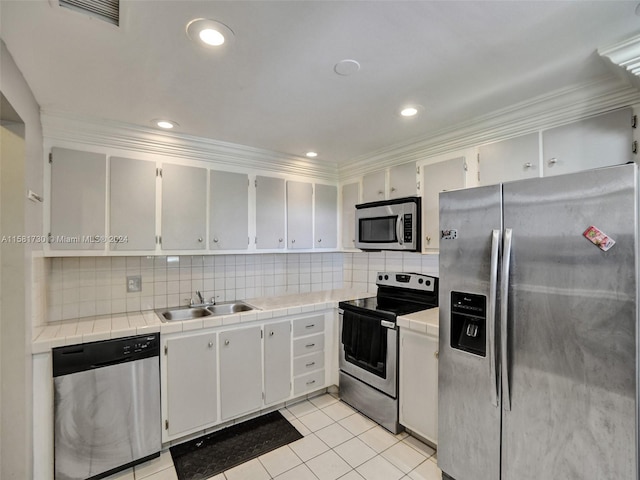 kitchen featuring stainless steel appliances, tasteful backsplash, white cabinetry, sink, and light tile floors