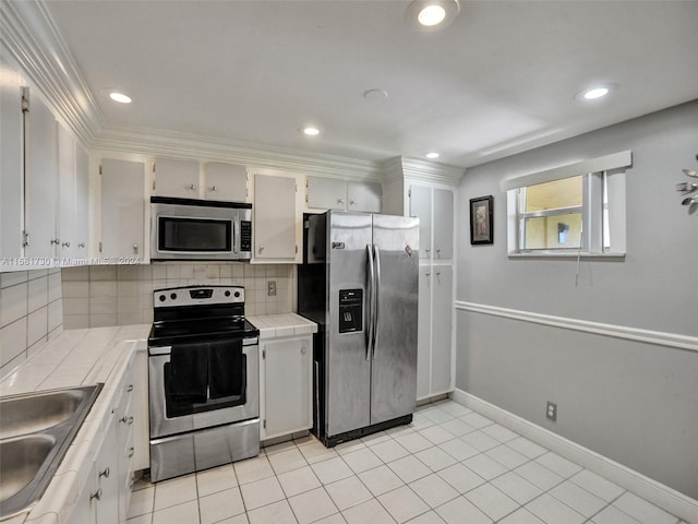 kitchen featuring stainless steel appliances, tasteful backsplash, white cabinetry, tile counters, and light tile floors