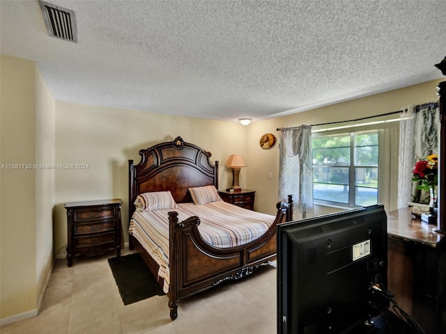 bedroom with a textured ceiling and light tile floors