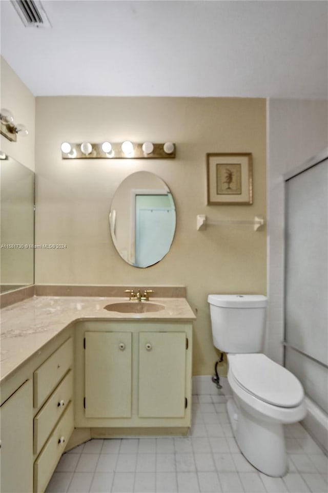 bathroom with tile flooring, oversized vanity, and toilet