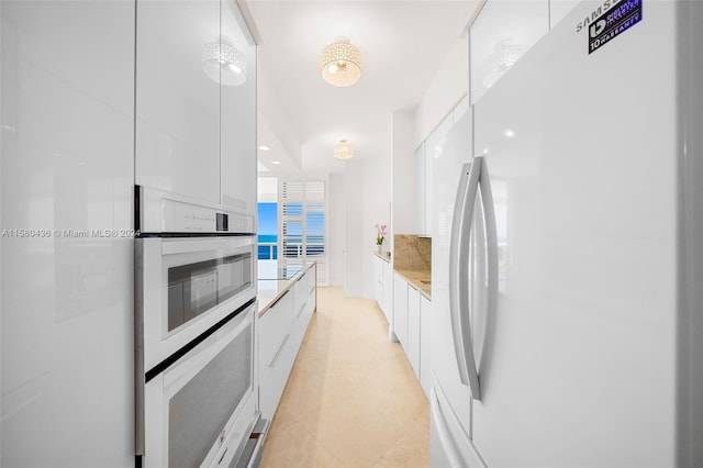 kitchen featuring white appliances, light tile floors, and white cabinetry