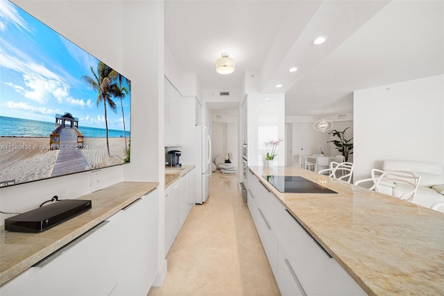 kitchen with a water view, light tile floors, white fridge, white cabinets, and black electric stovetop