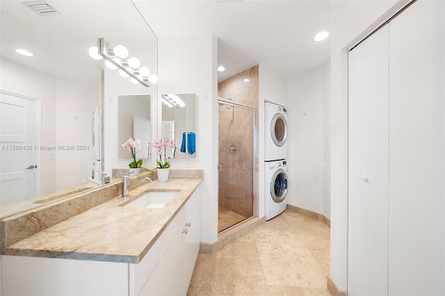 bathroom with tile flooring, stacked washer and clothes dryer, large vanity, and a shower with shower door