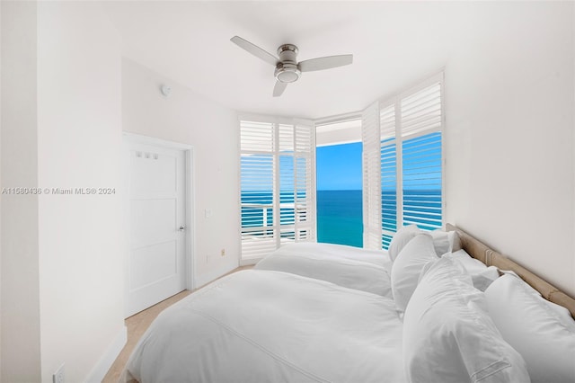 bedroom with ceiling fan and a water view