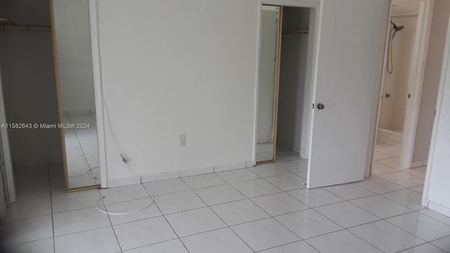 unfurnished bedroom featuring a spacious closet, a closet, and light tile flooring