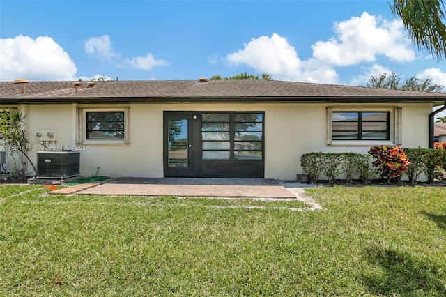 rear view of house with central AC, a lawn, and a patio