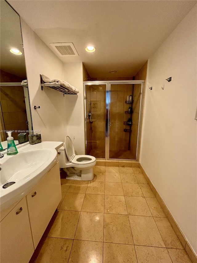 bathroom featuring tile floors, a shower with door, toilet, and vanity