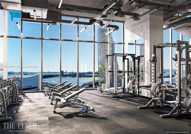 exercise room featuring a towering ceiling, expansive windows, and a water view