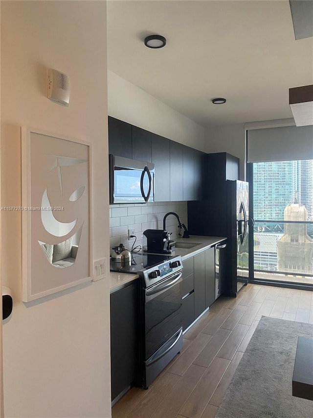 kitchen featuring sink, hardwood / wood-style flooring, black appliances, and backsplash