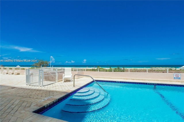 view of swimming pool featuring a water view and a patio area