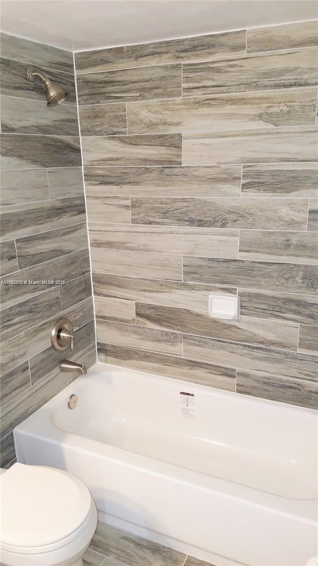 bathroom with toilet and tiled shower / bath combo