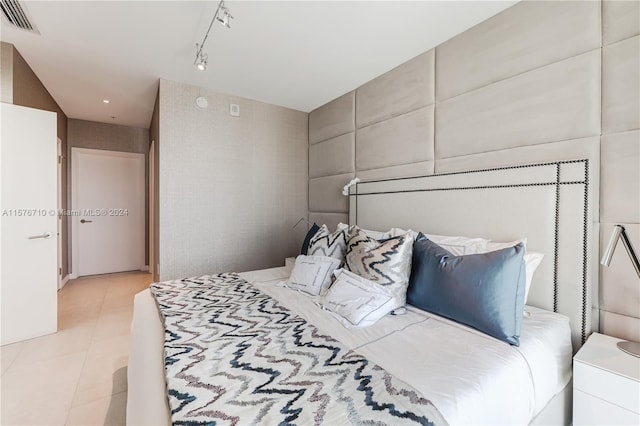 bedroom with light tile patterned floors and track lighting