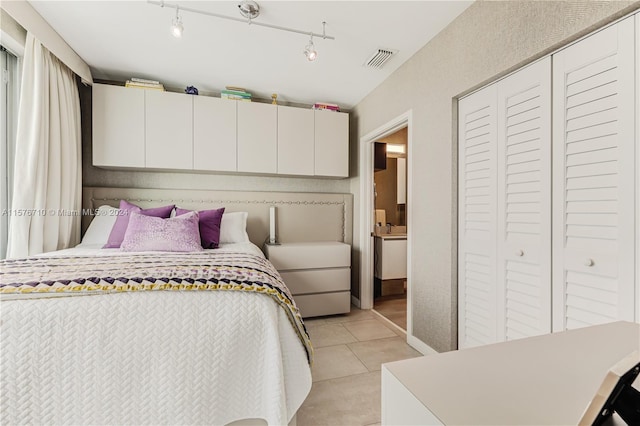 tiled bedroom with rail lighting and a closet