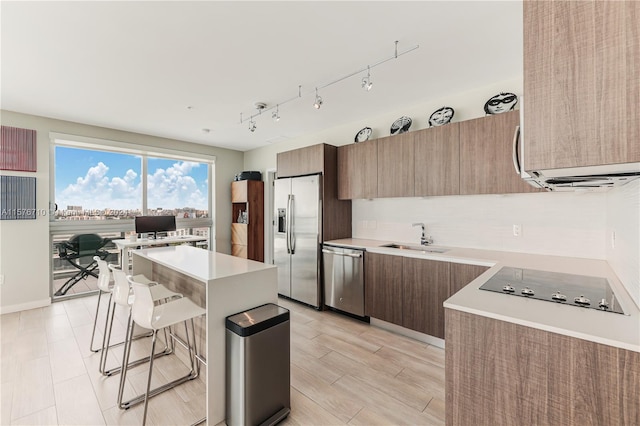 kitchen featuring sink, a center island, a kitchen bar, decorative backsplash, and appliances with stainless steel finishes