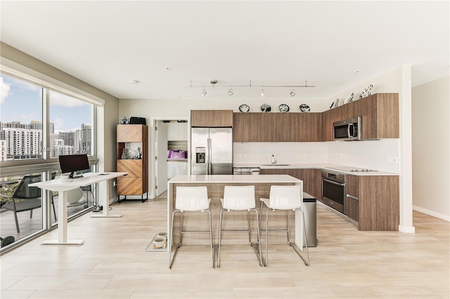 kitchen with a kitchen breakfast bar, a center island, stainless steel appliances, and sink