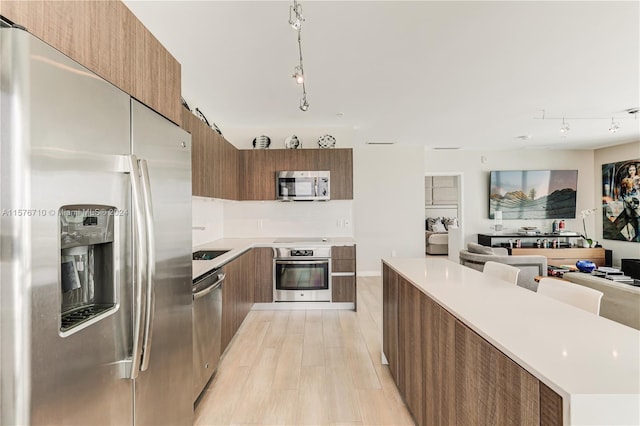 kitchen featuring light hardwood / wood-style flooring, stainless steel appliances, and track lighting