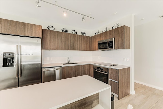 kitchen with tasteful backsplash, light hardwood / wood-style flooring, stainless steel appliances, and sink