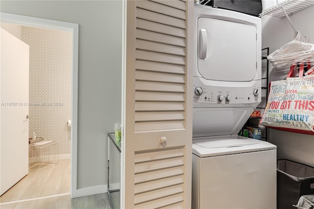 washroom with light wood-type flooring and stacked washer / drying machine