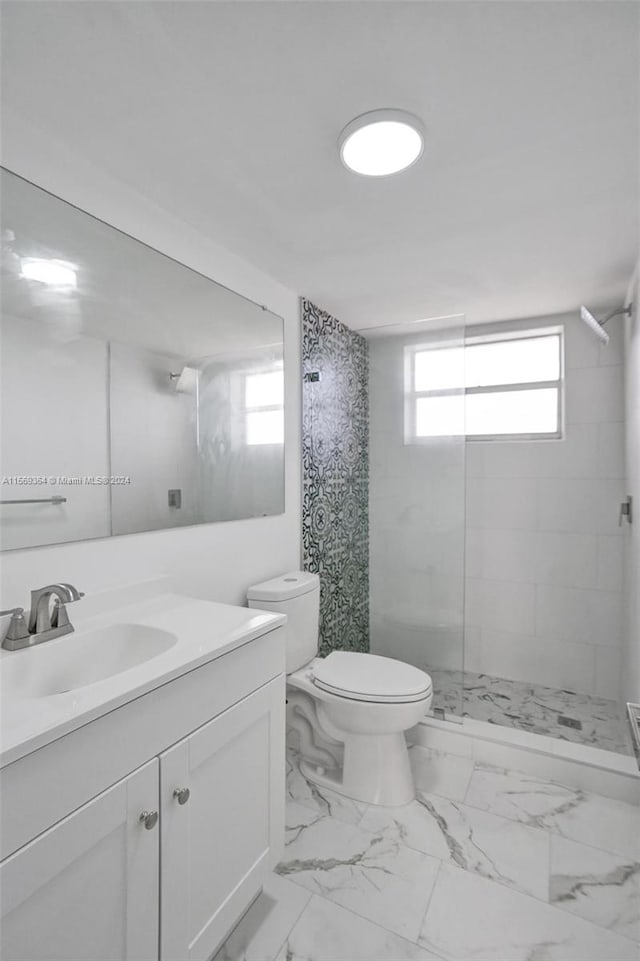 bathroom with vanity, tiled shower, toilet, and tile patterned flooring