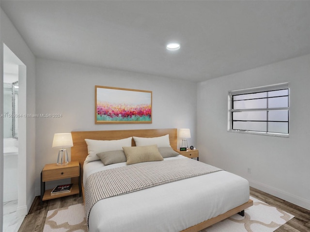 bedroom featuring hardwood / wood-style flooring and connected bathroom