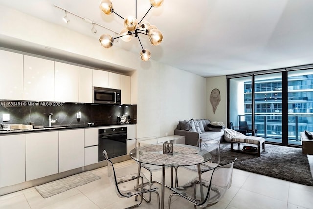 kitchen with oven, white cabinetry, light tile floors, tasteful backsplash, and track lighting