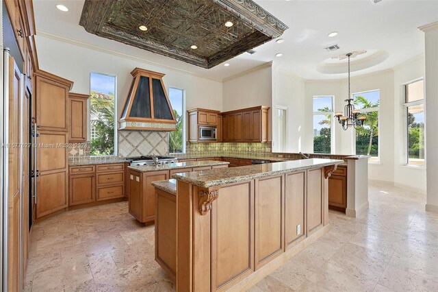 kitchen featuring stone counters, tasteful backsplash, kitchen peninsula, and custom exhaust hood