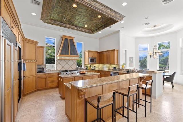 kitchen featuring kitchen peninsula, tasteful backsplash, built in appliances, and custom exhaust hood