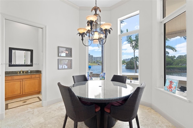 dining space featuring a water view, sink, a notable chandelier, light tile floors, and ornamental molding