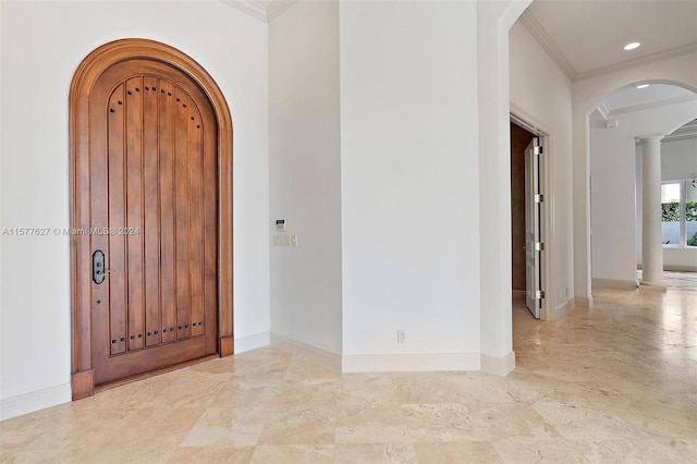 tiled entryway featuring crown molding and ornate columns