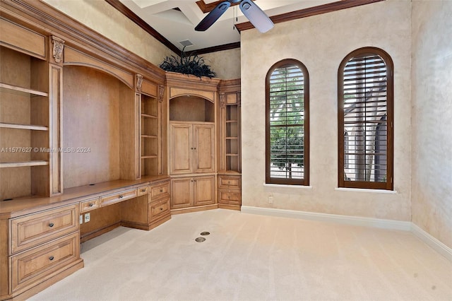 unfurnished office with ceiling fan, built in desk, light carpet, coffered ceiling, and ornamental molding