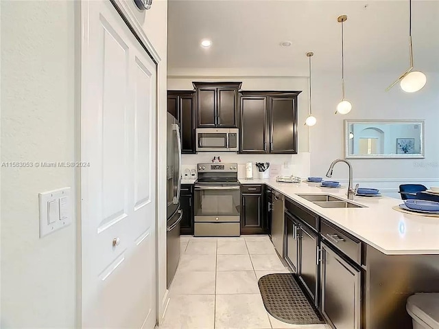 kitchen with dark brown cabinetry, appliances with stainless steel finishes, light tile floors, sink, and pendant lighting