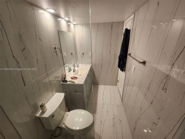 bathroom featuring vanity, toilet, and tile walls