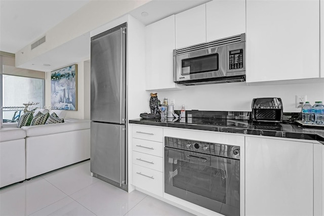 kitchen with white cabinets, light tile patterned flooring, and black appliances