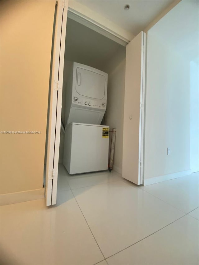 washroom with light tile patterned flooring and stacked washing maching and dryer