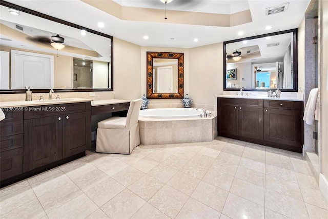 full bath with ceiling fan, two vanities, visible vents, a bath, and a tray ceiling