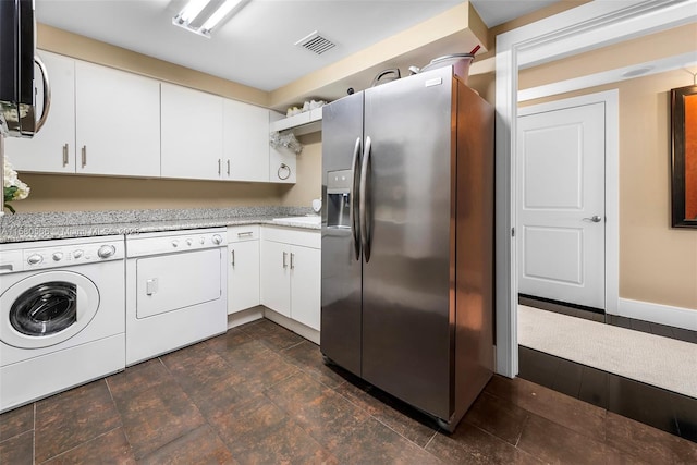 clothes washing area featuring laundry area, visible vents, baseboards, washer and dryer, and stone finish floor