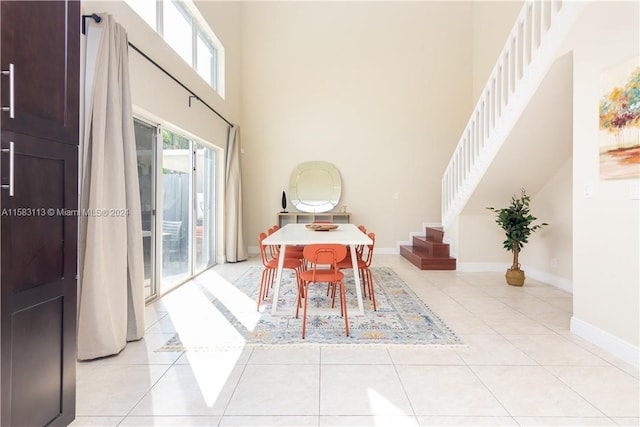 dining room with a towering ceiling and light tile floors