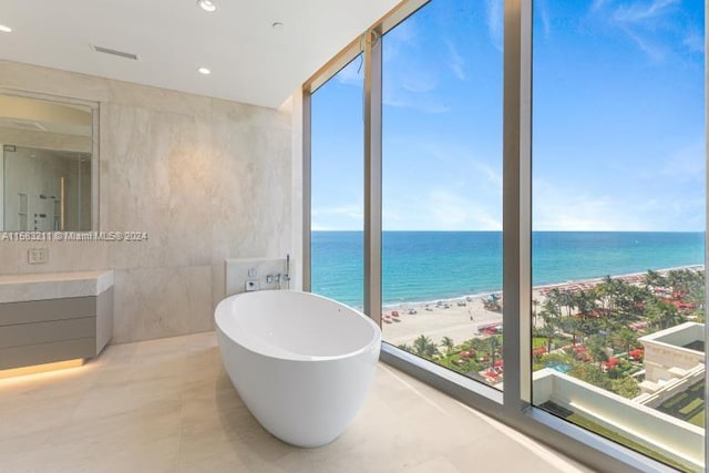 bathroom with a beach view, a water view, tile walls, and tile floors