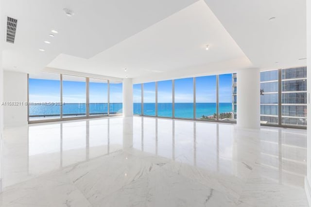 unfurnished room featuring tile floors, floor to ceiling windows, and a water view