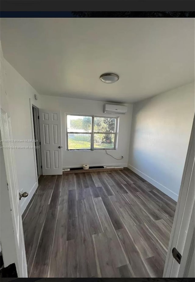 unfurnished room featuring dark hardwood / wood-style floors and an AC wall unit