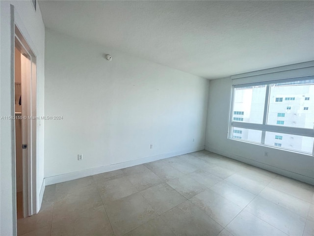 unfurnished room with a textured ceiling and light tile floors