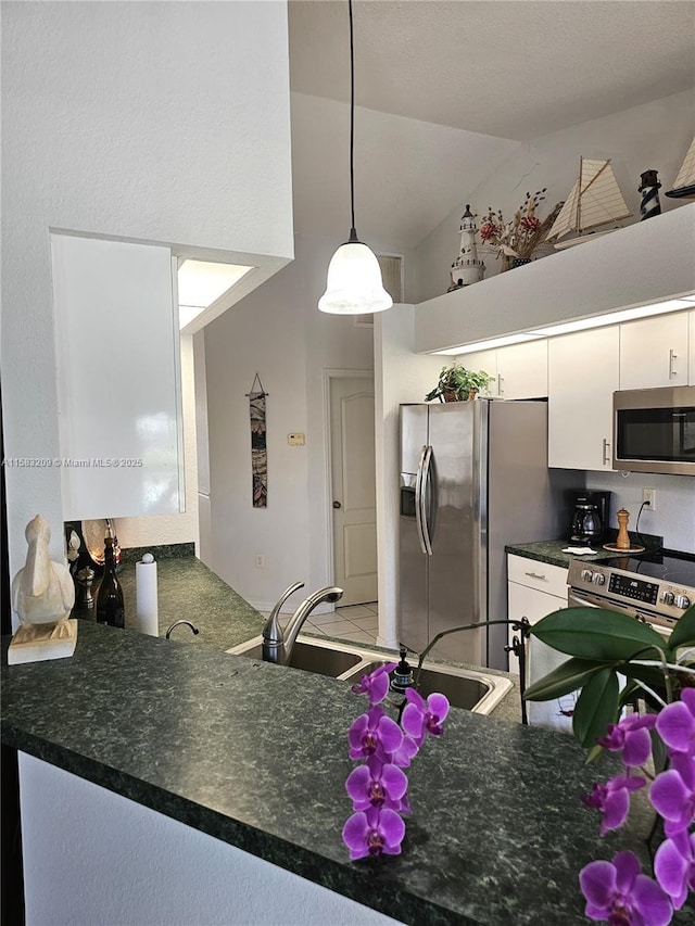 kitchen featuring high vaulted ceiling, white cabinetry, sink, hanging light fixtures, and stainless steel appliances