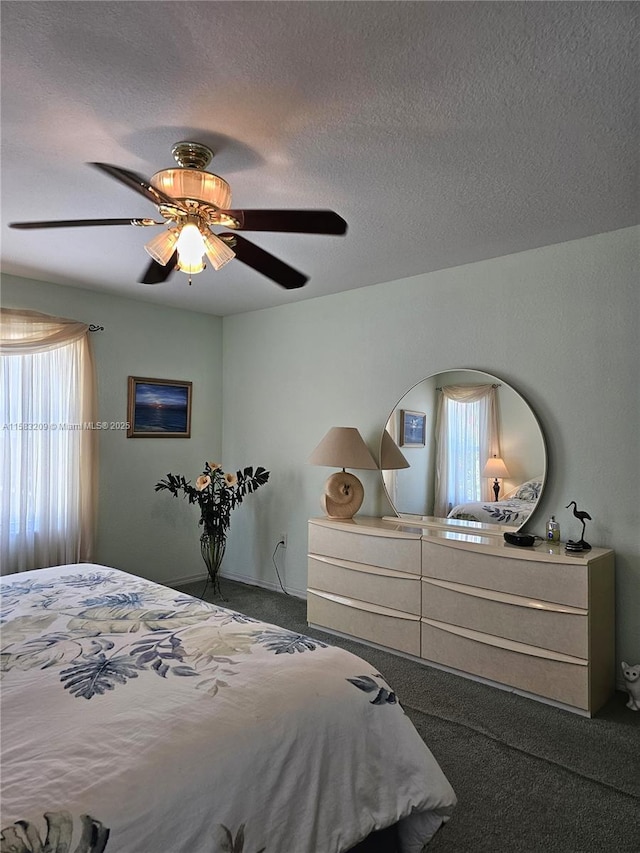 carpeted bedroom featuring ceiling fan and a textured ceiling