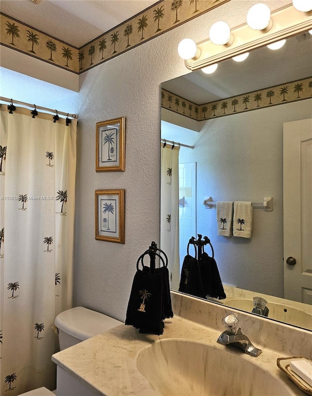 bathroom with vanity, toilet, a shower with shower curtain, and a textured ceiling