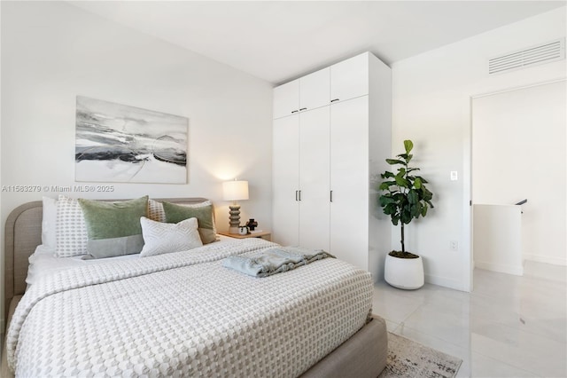 bedroom with light tile patterned floors, visible vents, baseboards, and a closet