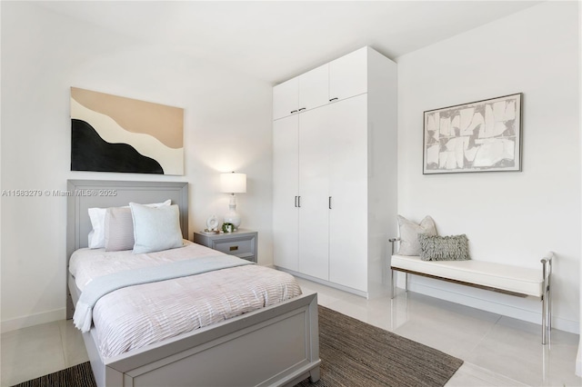 bedroom with tile patterned flooring, baseboards, and a closet