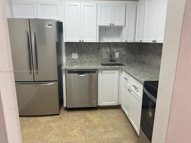 kitchen with stainless steel electric stove, light stone countertops, white cabinetry, decorative backsplash, and light tile patterned floors