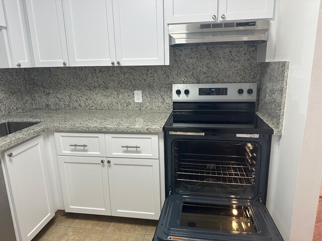 kitchen featuring stainless steel electric stove, white cabinetry, tasteful backsplash, light stone counters, and light tile patterned floors