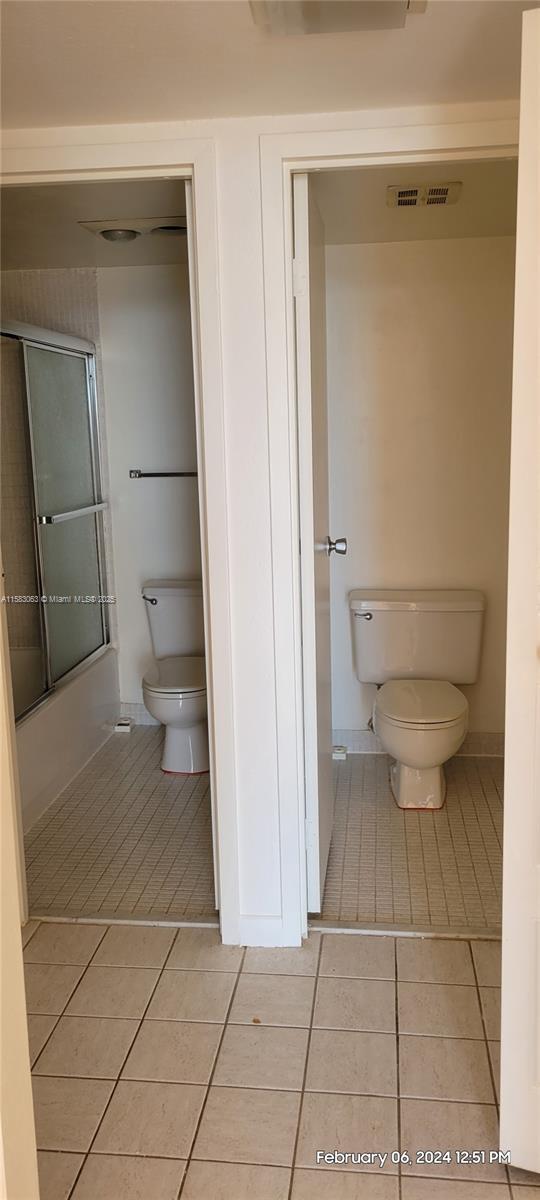 bathroom featuring toilet, enclosed tub / shower combo, and tile patterned floors